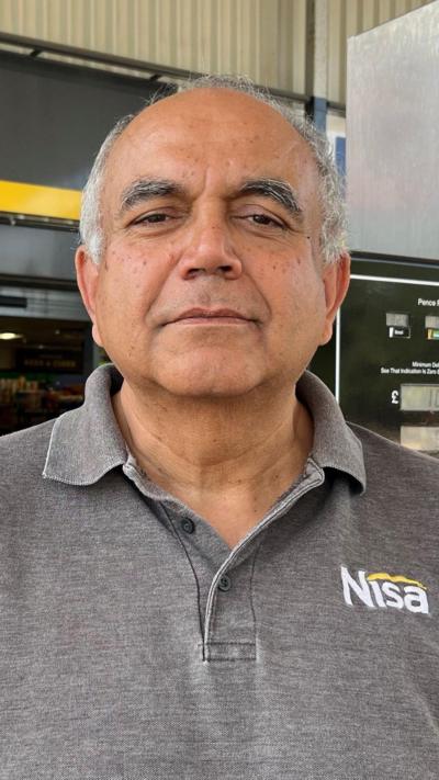 A balding man with grey hair wearing a grey polo shirt