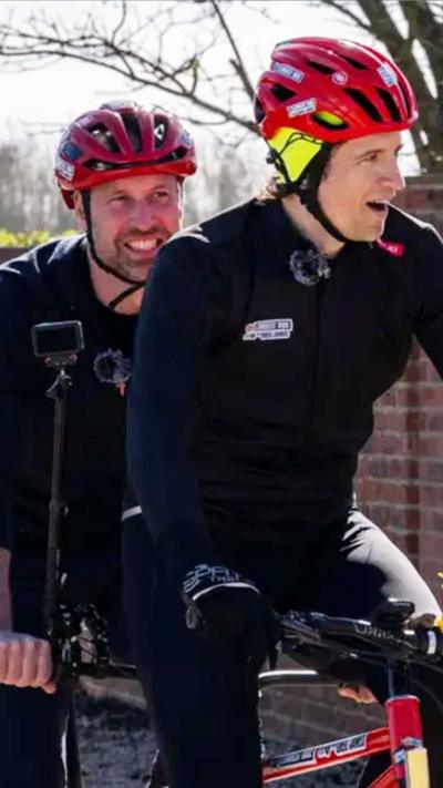 Prince William and Greg James ride on a tandem bike together.