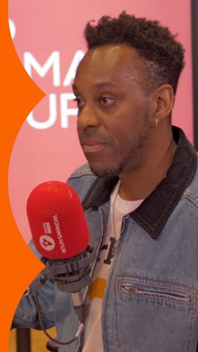 Elliott in the Woman's Hour studio. He has short black hair and wears a denim jacket