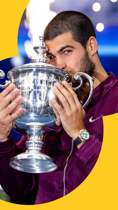 Carlos Alcaraz, wearing a purple Nike jacket, kissing the US Open trophy.