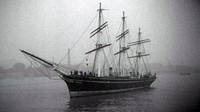 Black and white image of the naval ship, the 'Cutty Sark', showing three sails and a bowsprit.