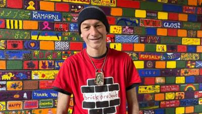 Gloucester Brick Project founder Dan Petley standing in front of the painted wall