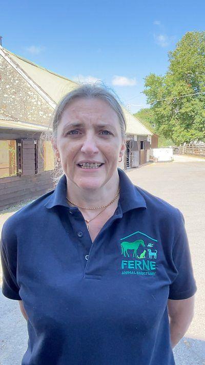 A woman looking at the camera with a Ferne Animal Sanctuary logo on her t shirt.