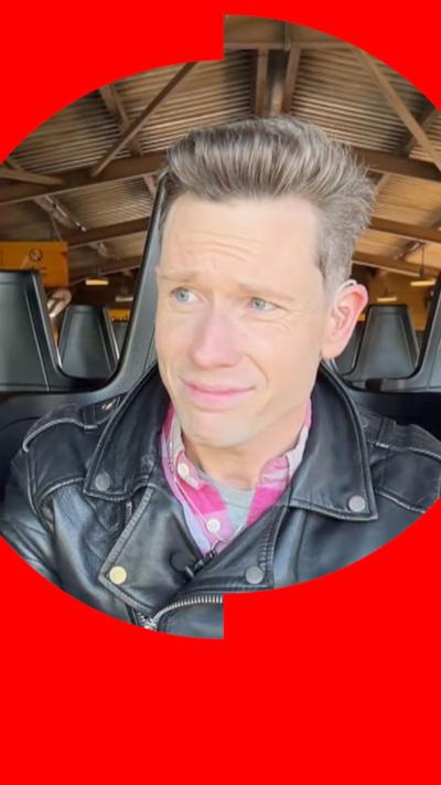 Peter Ruddick is sat on a roller coaster wearing a black leather jacket.