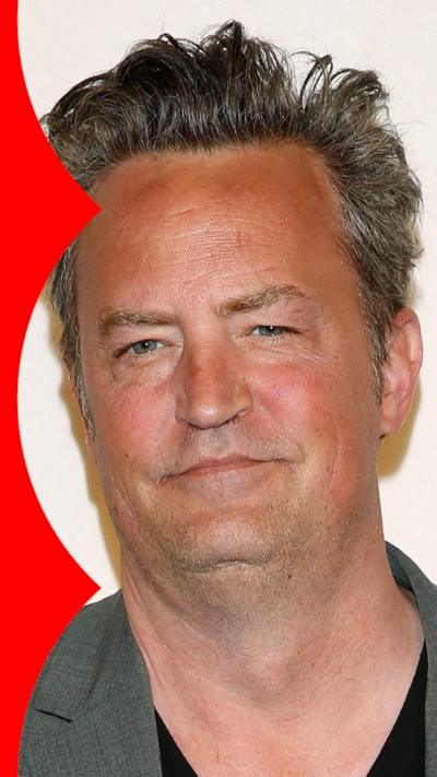 Matthew Perry has a neutral expression wearing a grey jacket and black shirt