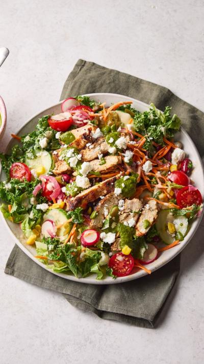 A white plate sits on a grey napkin. It contains a large salad with lots of different ingredients.