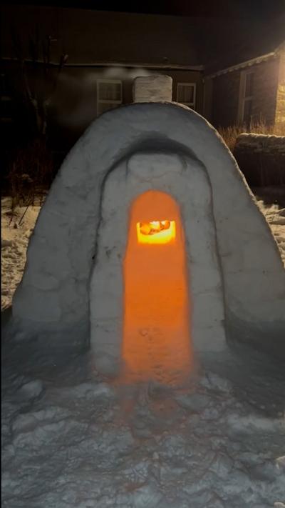 A fire glows bright orange inside an igloo in a garden in Orkney