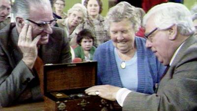 Arthur Negus evaluating a wooden tea caddy in front of the owners on Antiques Roadshow.