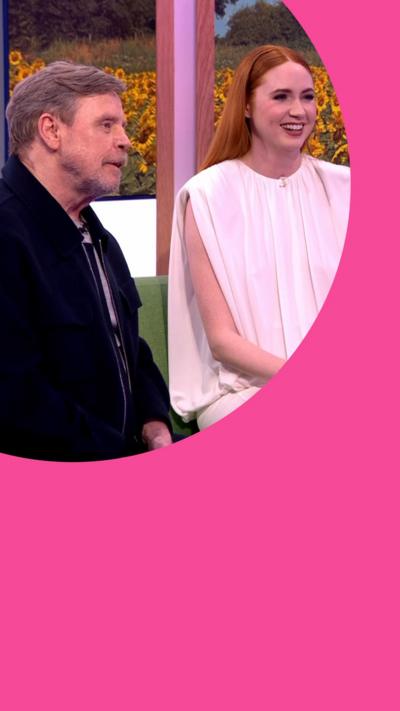 Mark Hamill in a dark jacket and Karen Gillan in a light coloured dress sit on The One Show sofa together.