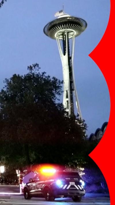 The Seattle space needle in the evening sky. There is a police car in the foreground.