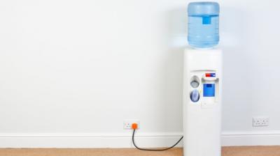 A water cooler in front of a blank white wall