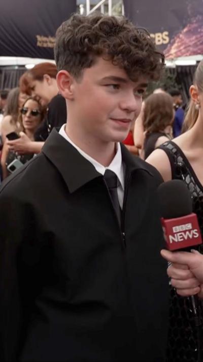 Owen Cooper stands in front of a BBC mic on Emmys red carpet