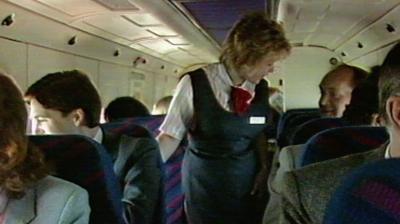 Air stewardess assisting passengers inside a small commuter plane.