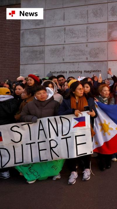 People holding Philippines flags in front of an ICC prison and holding a sign saying 'stand Duteret'