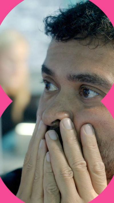Rav Wilding in the Scam Interceptors HQ, looking worried with his hands over his mouth.