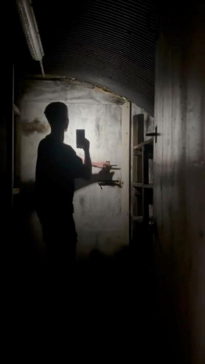 A silhouetted man standing in front of a bolted door 