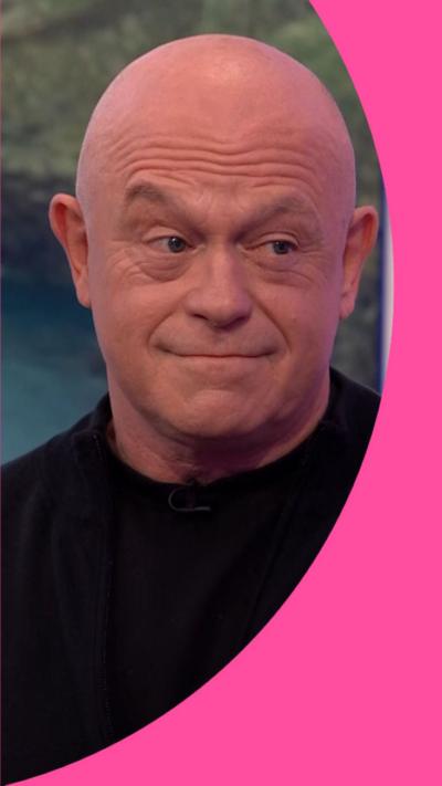 Ross Kemp is looking across to somebody off camera to the right of the screen and is wearing a black shirt