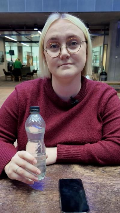 Georgina Hayes sits at a table, holding a bottle of water