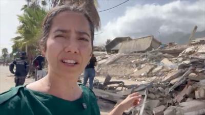 Vanessa Silva reporting from Venezuela showing destroyed buildings behind her