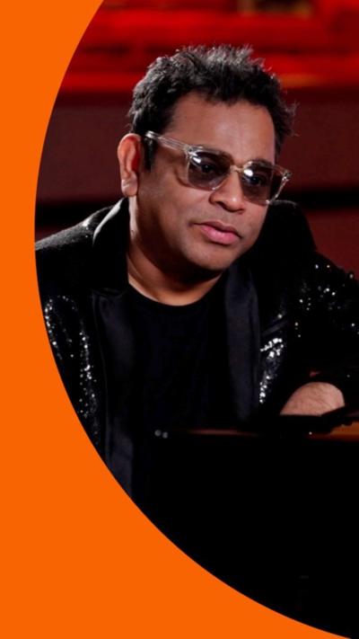 A man, AR Rahman, wears sunglasses and a black suit.