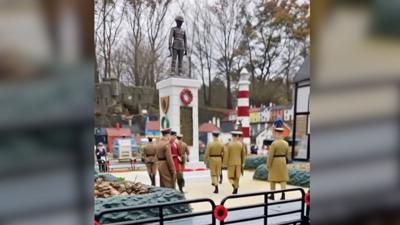 A still from the video showing computer generated soldiers in uniform standing in front of its war memorial