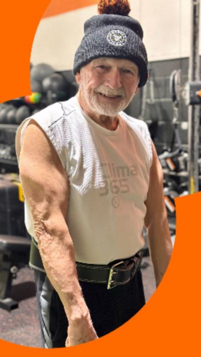 A man wearing a grey bobble-hat, sleeveless T-shirt and black gym shorts.