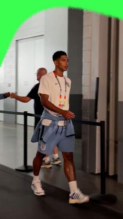 Jude Bellingham arriving at the Atlanta Stadium in a white shirt and blue shorts.
