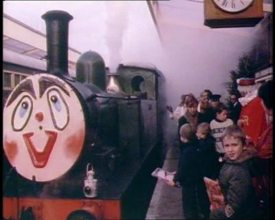 A crowd of parents and children stand beside Santa's steam train