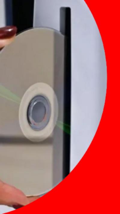 A woman's hand putting a disc into a PlayStation console.