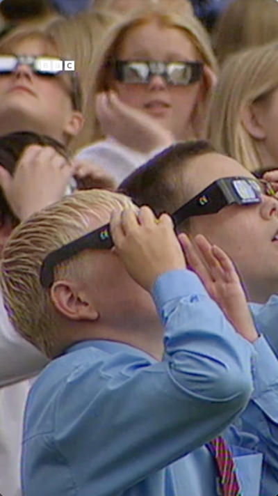 young children looking at the sky with eclipse glasses on