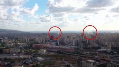 View of Beirut skyline, where two circles are outlining smoke appearing to come out of explosions across the city