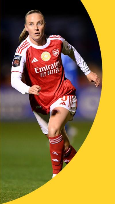 Beth Mead has blonde hair and is running on a football pitch wearing her red Arsenal kit with long white sleeves, white shorts and red socks.