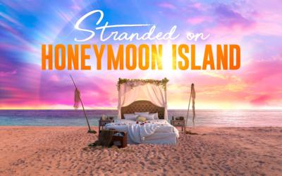 A sandy beach with a colourful pink blue and yellow sky and a large bed on the beach with a logo reading Stranded on Honeymoon Island in the sky above it
