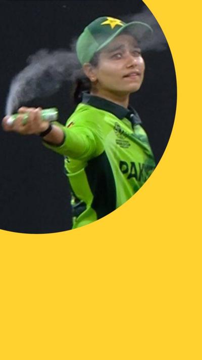 A woman in a green Pakistan shirt and a green baseball cap sprays an aerosol