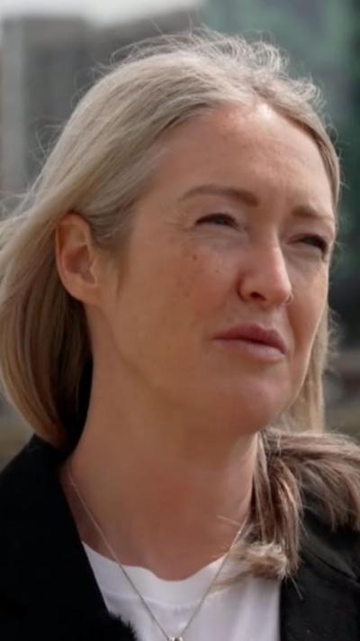 Esther ghey with short blonde hair wearing a white t shirt with silver necklace.