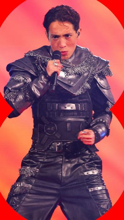 Kyle Alessandro performing on stage wearing a futuristic grey chain armour suit.