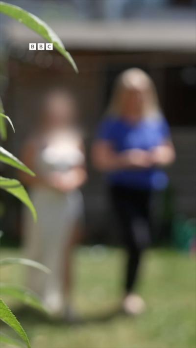 A blurred photo of two people walking on grass.
