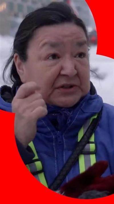 A woman outside in Greenland, wearing a blue coat.