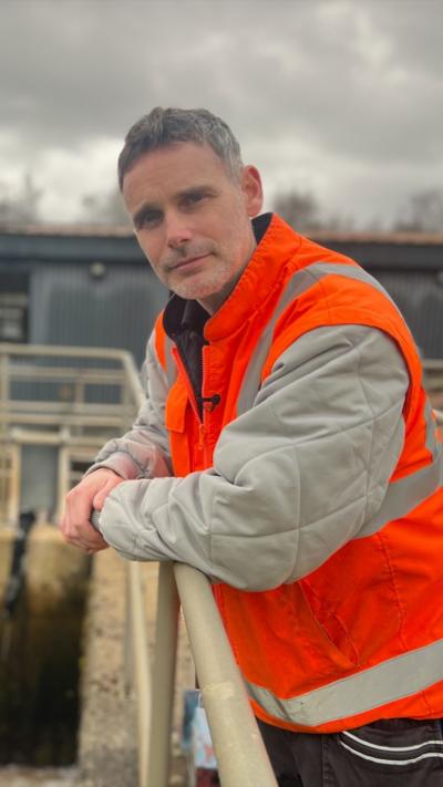 Man in high vis leans on fence