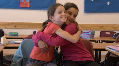 Two school girls hug