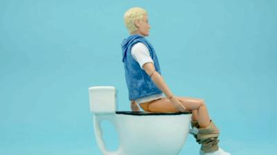 Image of an articulated doll sitting on the loo