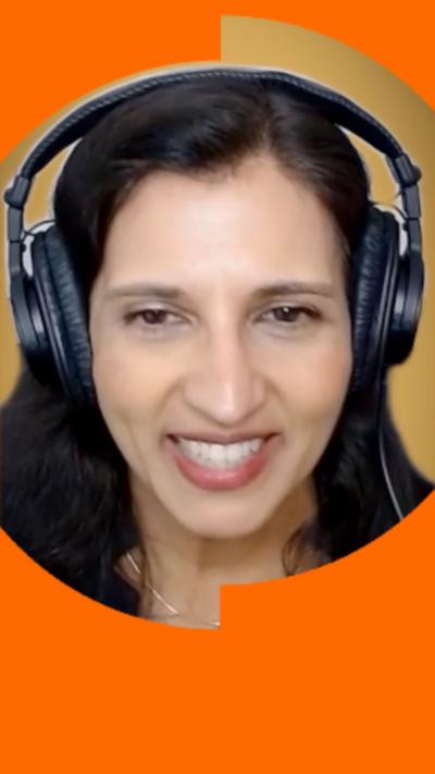 A woman with long dark hair, wearing radio headphones and a red top, smiles into the camera.