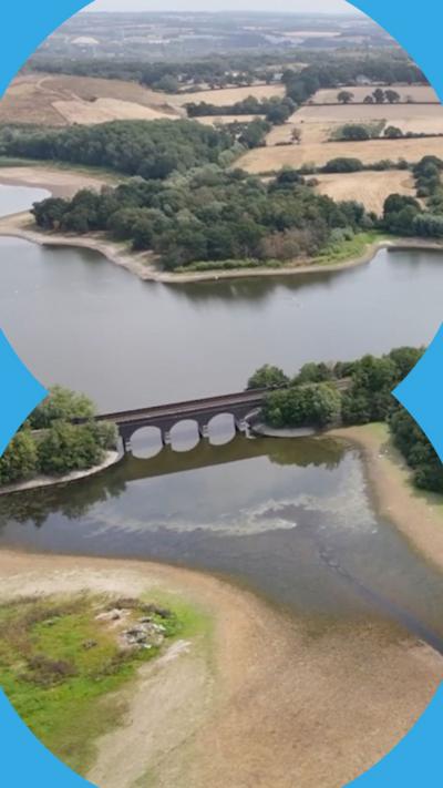 Aerial view of a stone railway viaduct crossing a low reservoir