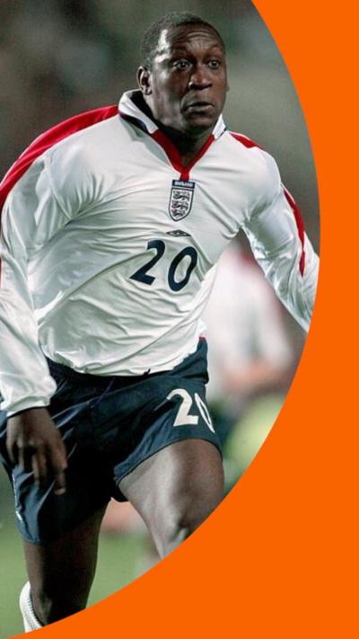 Emile Heskey wears an England football kit with number 20 on it.