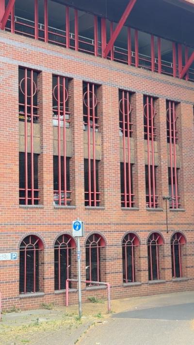 Queen's Road multi-storey car park, in Reading, Berkshire. It's a large brick building with open windows with red bars across them.