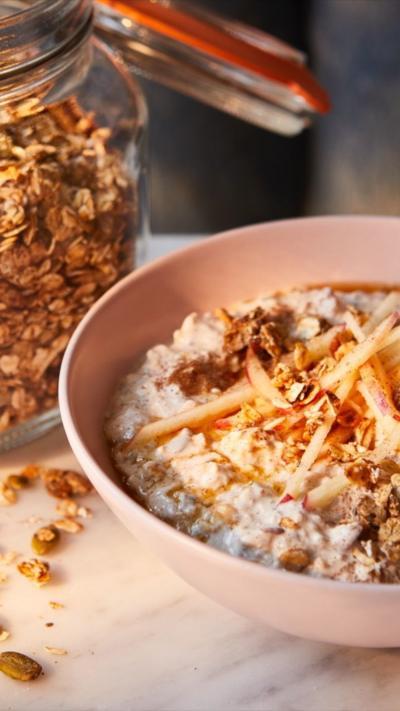 A glass jar of oats sits next to a pink bowl of oats with a spoon in it