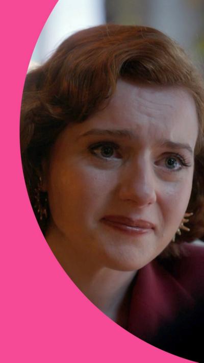 An upset red haired woman, Diana, leans in to a conversation with Michael