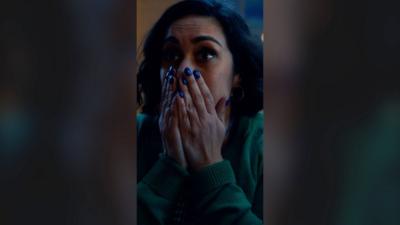 A woman looks surprised and holds her hands over her mouth