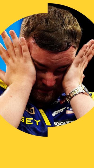 A man with short, brown hair holds his hands up to his face in distress