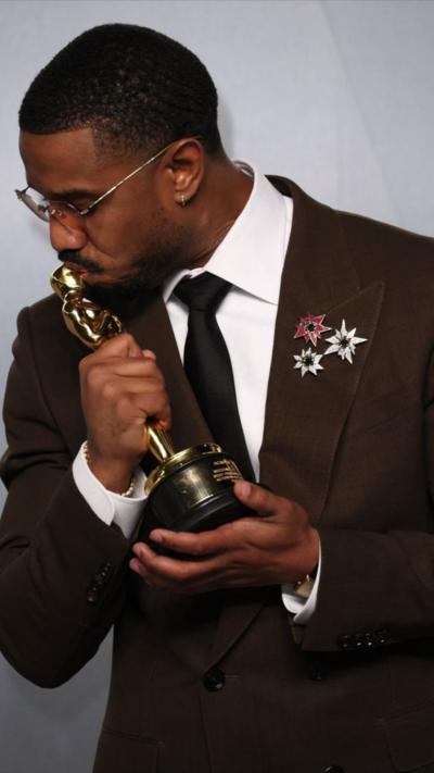 Michael B. Jordan wears a brown suit and sunglasses and kisses his Oscar